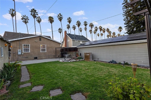 rear view of house featuring a lawn, solar panels, and a patio area