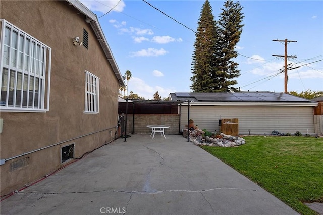 view of side of property featuring a yard, a patio area, and solar panels