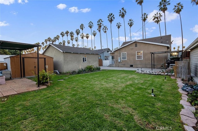 rear view of property featuring a patio, a lawn, and a storage unit