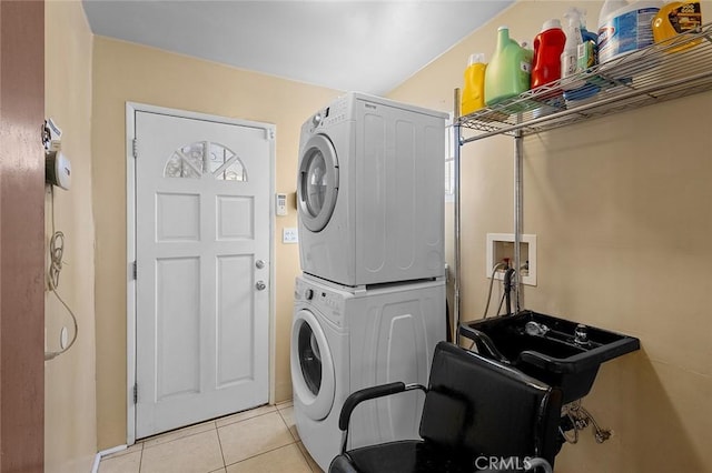 clothes washing area with light tile patterned floors and stacked washer and clothes dryer