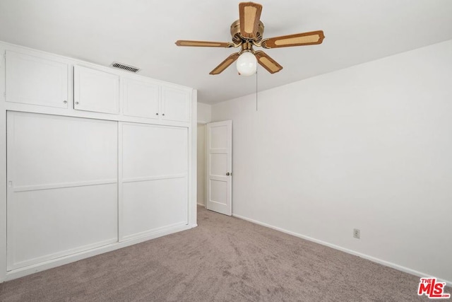 unfurnished bedroom with ceiling fan, a closet, and light carpet