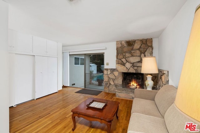 living room featuring light hardwood / wood-style flooring and a stone fireplace