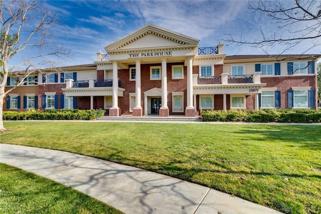 view of front of home with a balcony and a front lawn