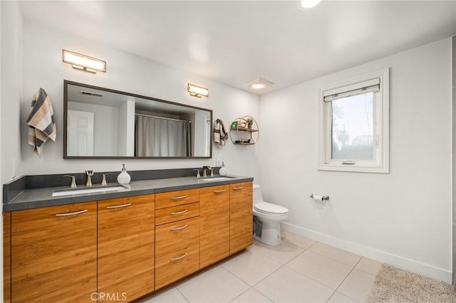 bathroom with toilet, vanity, and tile patterned floors