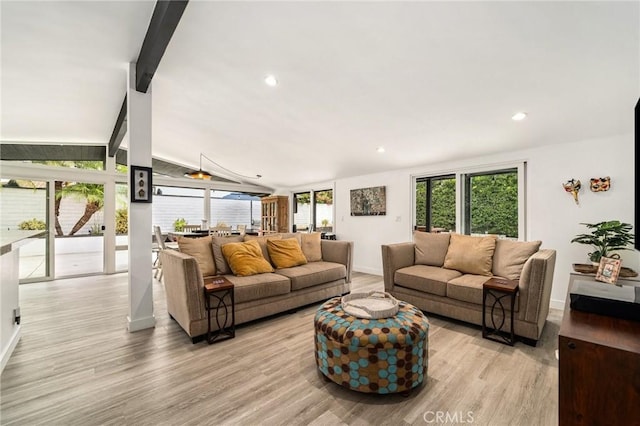 living room featuring lofted ceiling with beams and light hardwood / wood-style flooring