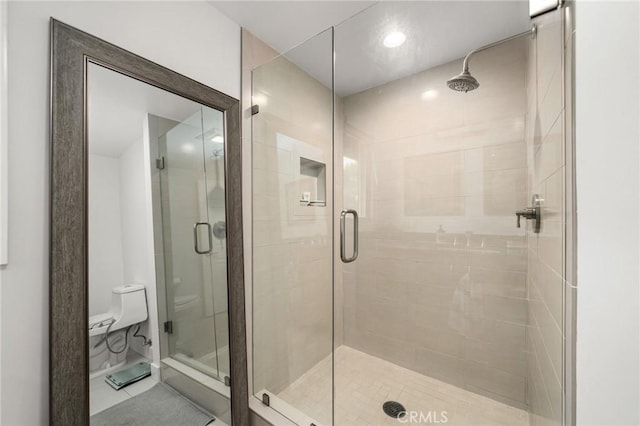 bathroom featuring tile patterned floors, toilet, and a shower with door