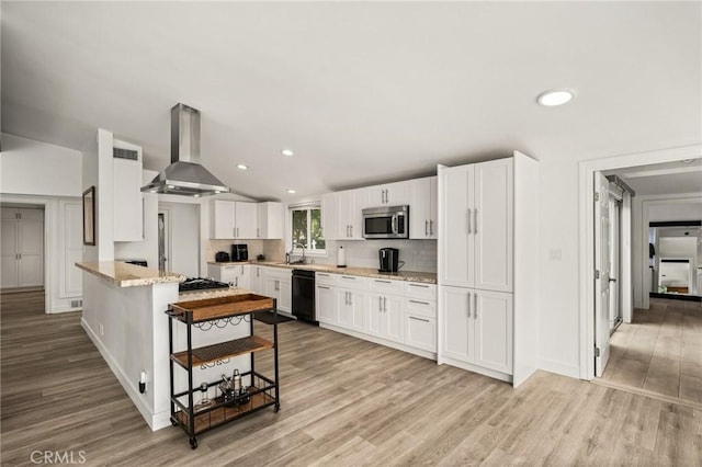 kitchen with white cabinets, light hardwood / wood-style flooring, light stone counters, and wall chimney range hood