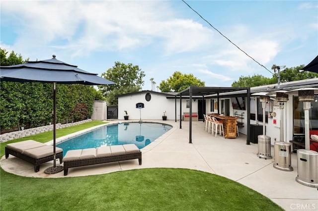 view of swimming pool featuring a lawn, a patio area, an outdoor bar, and glass enclosure