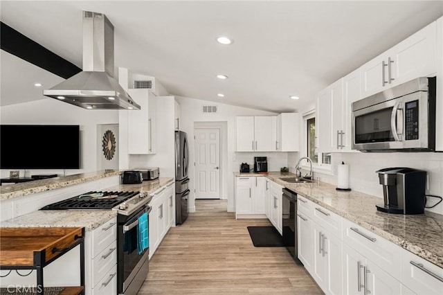 kitchen featuring light wood-type flooring, wall chimney exhaust hood, stainless steel appliances, sink, and white cabinetry