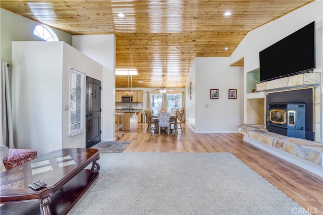 unfurnished living room featuring wood ceiling, light hardwood / wood-style flooring, a wood stove, vaulted ceiling, and ceiling fan