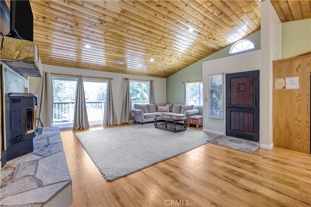 living room with light hardwood / wood-style flooring, high vaulted ceiling, a wood stove, and wood ceiling