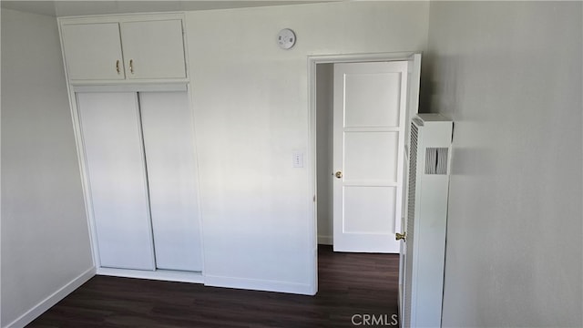 unfurnished bedroom with a closet and dark hardwood / wood-style floors