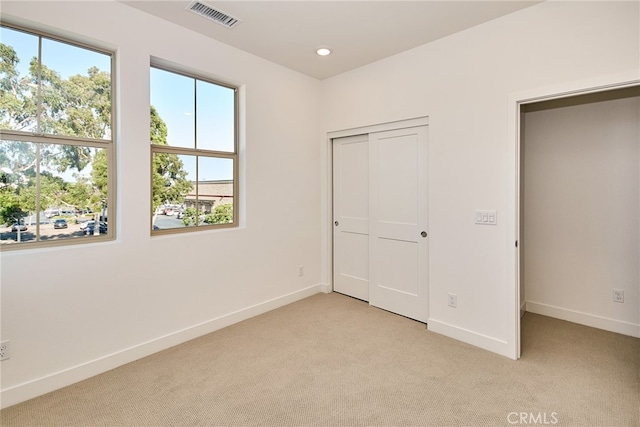 unfurnished bedroom with light carpet and a closet