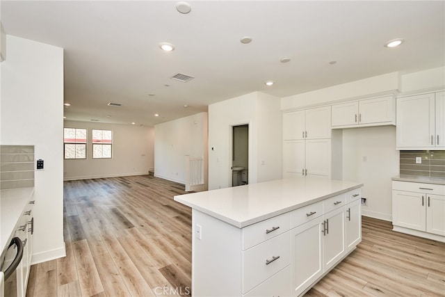 kitchen with white cabinets, light wood-type flooring, and backsplash