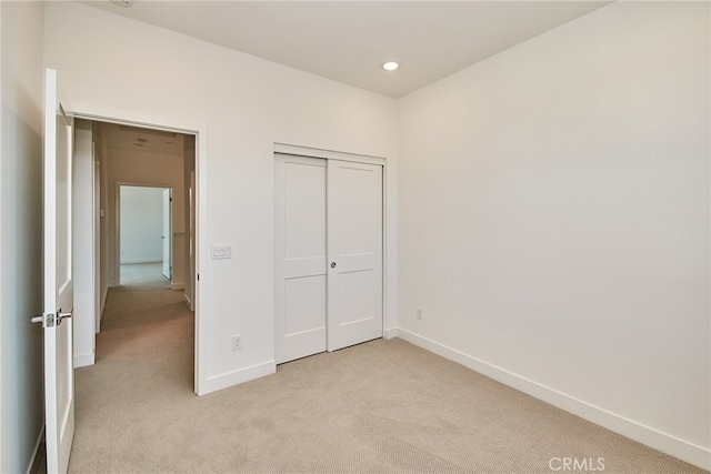 unfurnished bedroom with light carpet and a closet