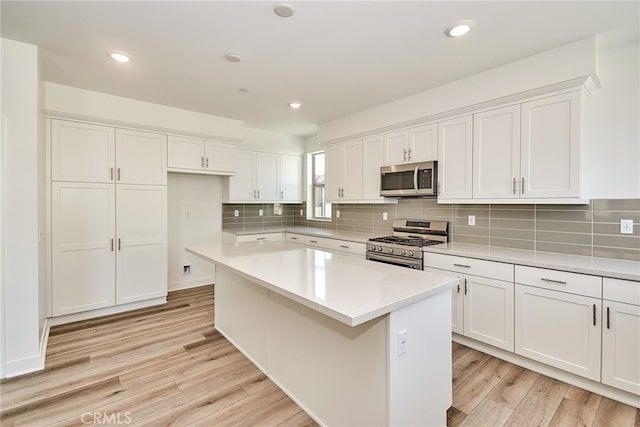 kitchen featuring appliances with stainless steel finishes, white cabinetry, a center island, and light hardwood / wood-style flooring