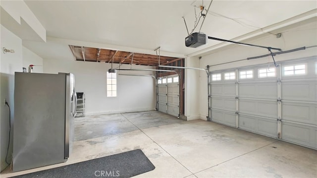 garage with stainless steel fridge and a garage door opener