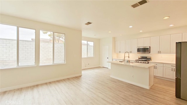 kitchen featuring visible vents, light wood-type flooring, white cabinetry, and appliances with stainless steel finishes