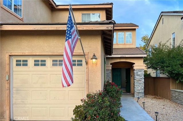 view of front of property featuring stone siding, stucco siding, and fence