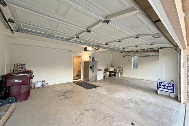 garage featuring stainless steel refrigerator with ice dispenser and a garage door opener