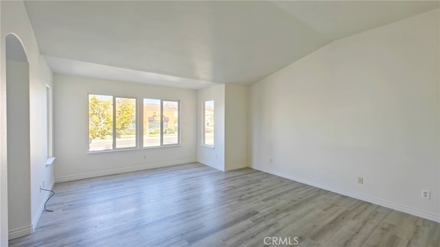 spare room with light hardwood / wood-style floors and lofted ceiling