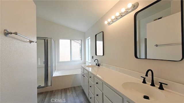 full bathroom featuring vaulted ceiling, wood finished floors, a sink, and a stall shower