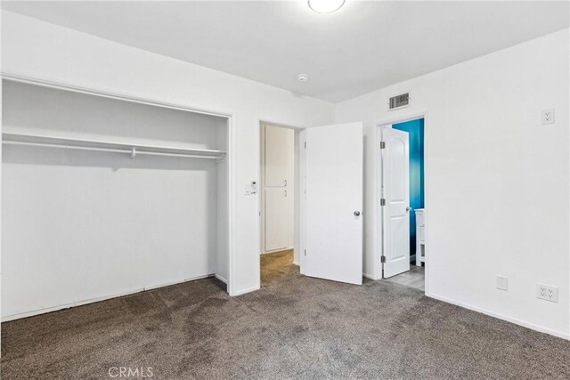 unfurnished bedroom featuring dark colored carpet and a closet