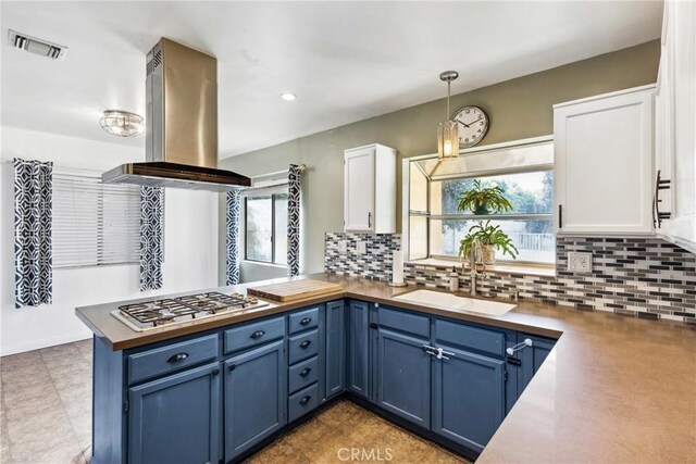 kitchen with blue cabinetry, sink, white cabinetry, island range hood, and hanging light fixtures