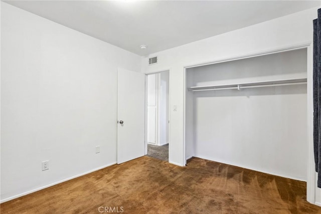 unfurnished bedroom with dark carpet and a closet