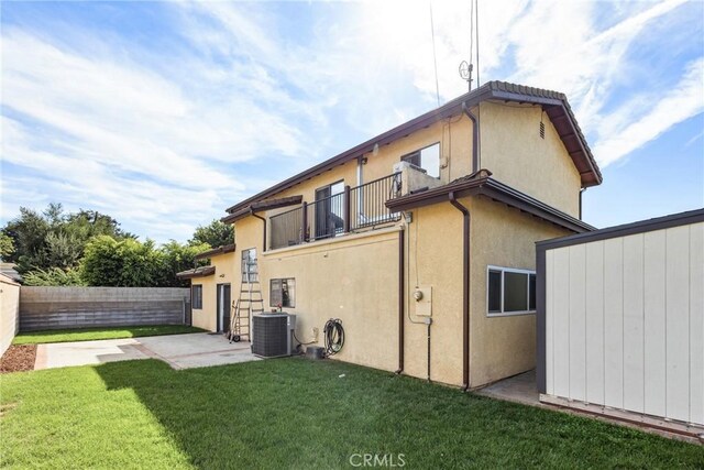 back of property with cooling unit, a balcony, a patio, and a lawn