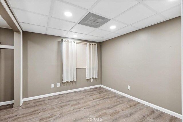 unfurnished room featuring a drop ceiling and light hardwood / wood-style flooring