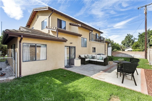 rear view of house featuring a balcony, outdoor lounge area, a patio, and a lawn