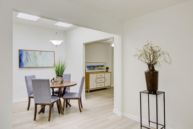 dining room with light wood-type flooring and a skylight