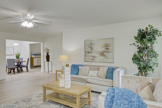 living room with ceiling fan, light hardwood / wood-style floors, and a textured ceiling