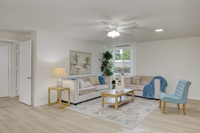 living room featuring ceiling fan, light hardwood / wood-style floors, and a textured ceiling