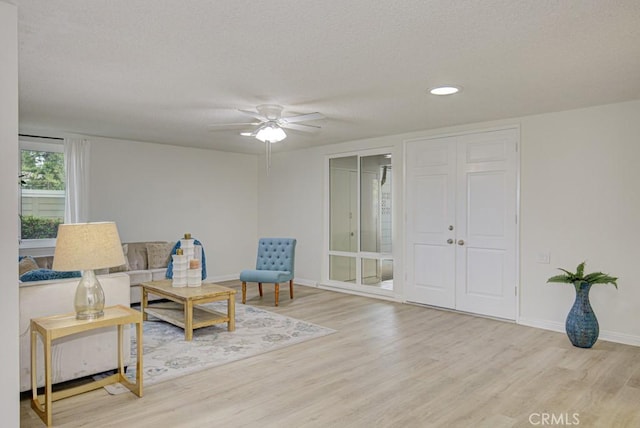 sitting room with a textured ceiling, light hardwood / wood-style flooring, and ceiling fan