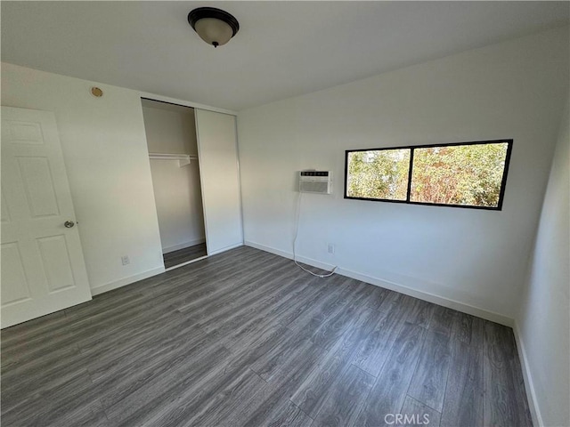 unfurnished bedroom featuring dark hardwood / wood-style flooring, a wall mounted AC, and a closet