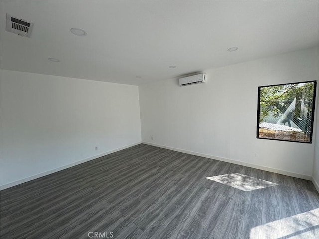 empty room featuring dark hardwood / wood-style floors and a wall unit AC