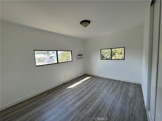 empty room with a wall mounted AC and dark wood-type flooring