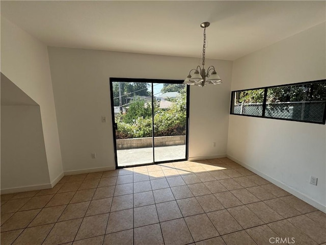 tiled empty room featuring an inviting chandelier