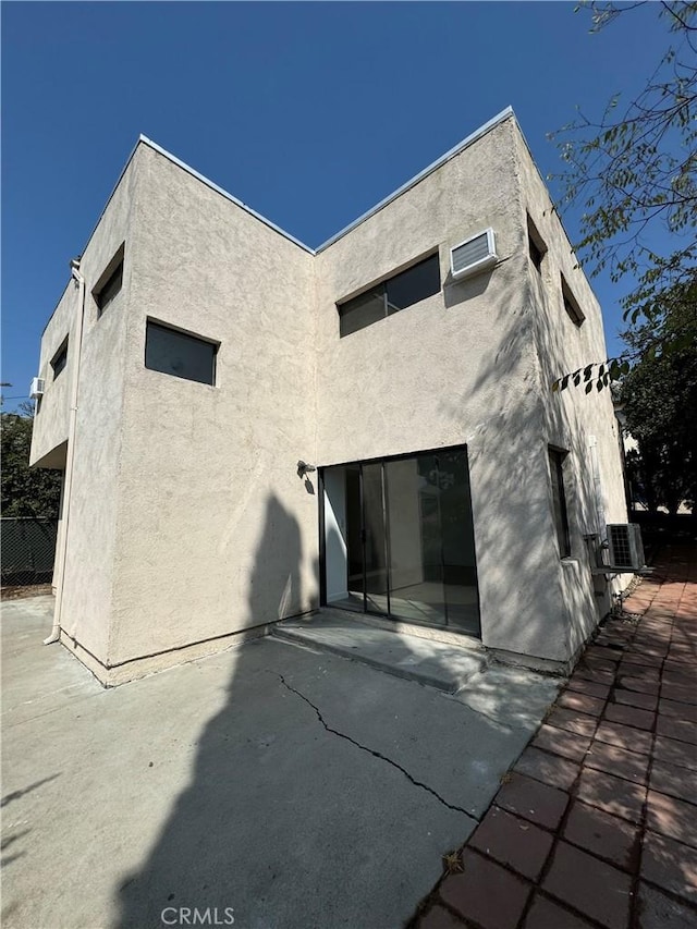 rear view of house with a wall mounted air conditioner and a patio