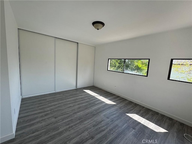 unfurnished bedroom with a closet and dark wood-type flooring