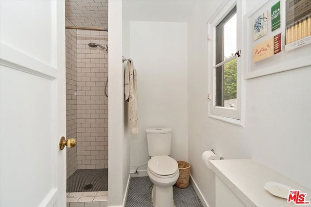 bathroom with toilet, a tile shower, and tile patterned floors