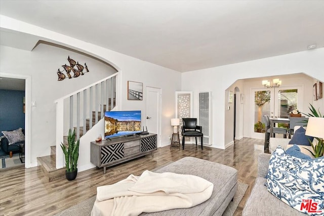 living room with wood-type flooring, french doors, and a notable chandelier