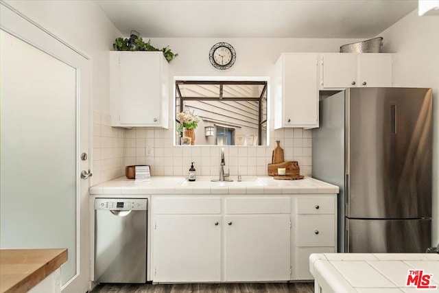 kitchen featuring dark hardwood / wood-style flooring, white cabinetry, tile counters, and appliances with stainless steel finishes