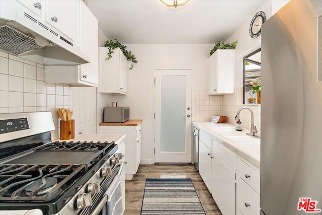 kitchen featuring stainless steel appliances, dark hardwood / wood-style flooring, backsplash, tile countertops, and white cabinets