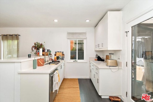 kitchen with white cabinets, sink, stainless steel dishwasher, hardwood / wood-style flooring, and kitchen peninsula