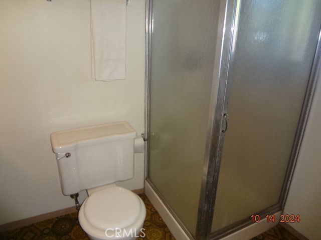 bathroom with toilet and a shower with door