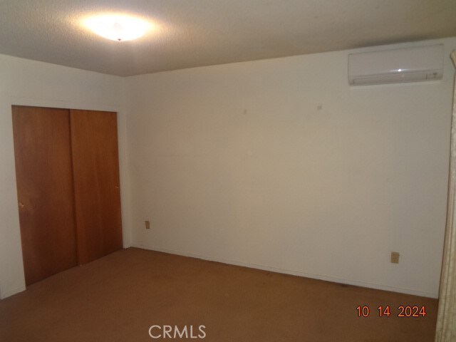 unfurnished bedroom with a closet and a wall mounted AC