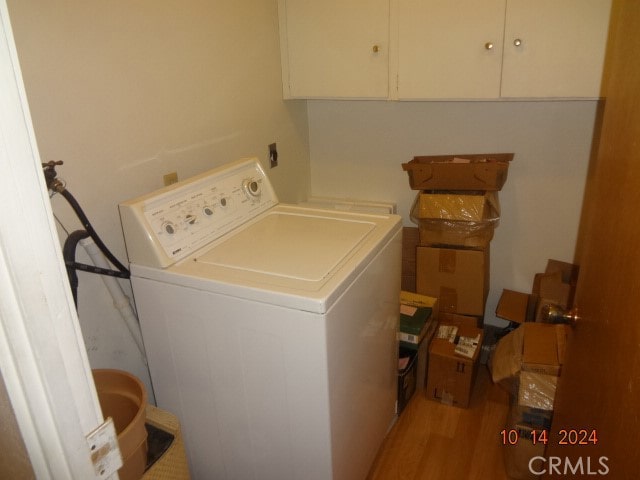 clothes washing area featuring light hardwood / wood-style flooring, cabinets, and washer / clothes dryer